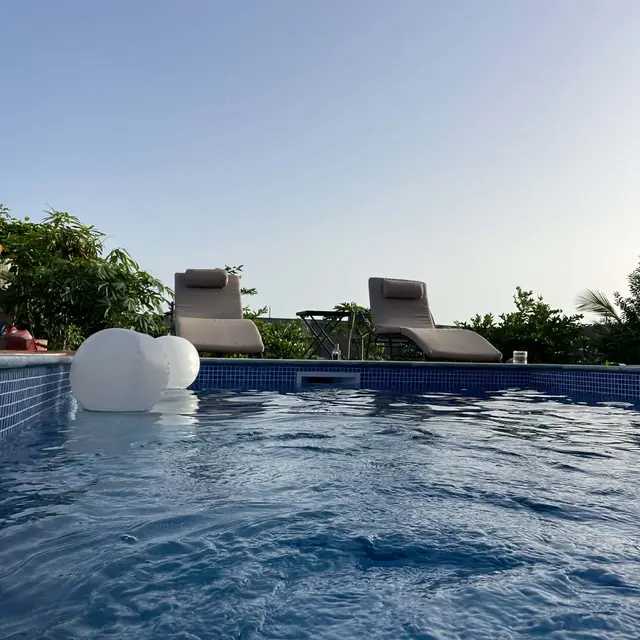 Piscina com bóias flutuantes e espreguiçadeiras num dia de céu limpo