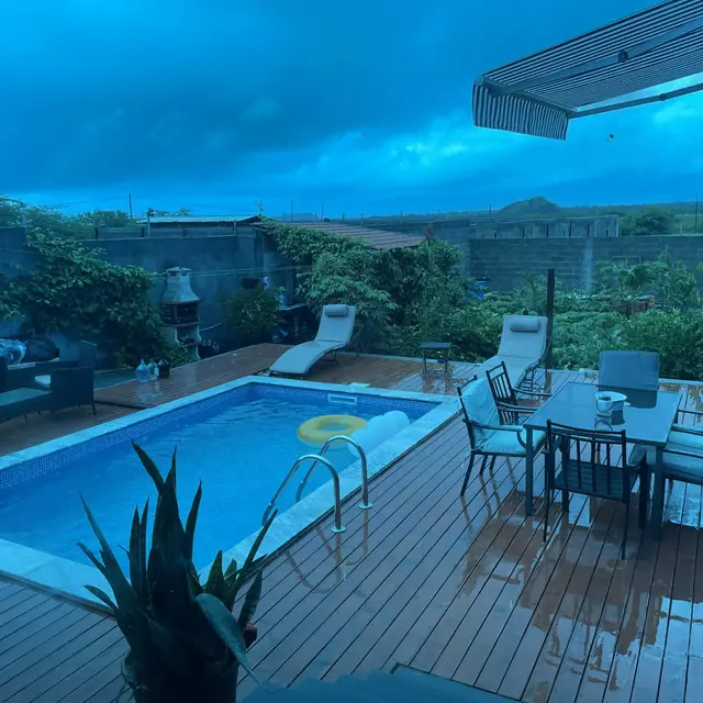 Deque da piscina e mesa de jantar exterior sob um céu de tempestade ao entardecer