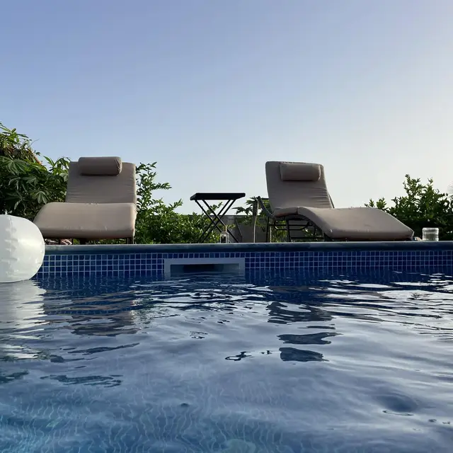 Espreguiçadeiras e bóias junto à piscina ao pôr do sol