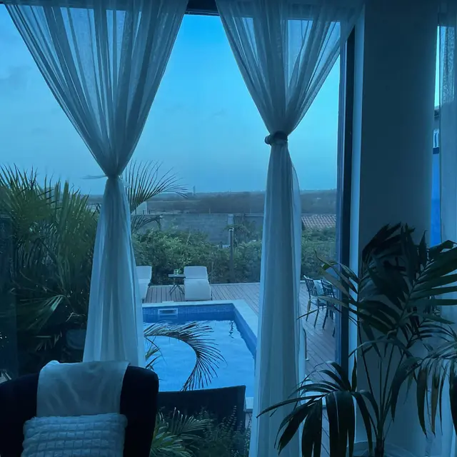 Vista da piscina através das cortinas translúcidas da sala